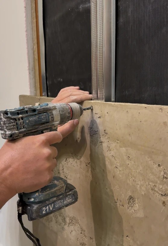 A Rumett panel being screw-fixed by hand through the panel face into a metal stud framework
