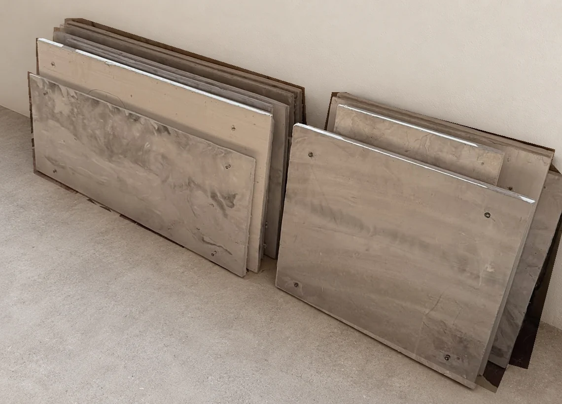 Rumett panels taken down from a wall, stacked in two rows against a wall with their screw holes visible